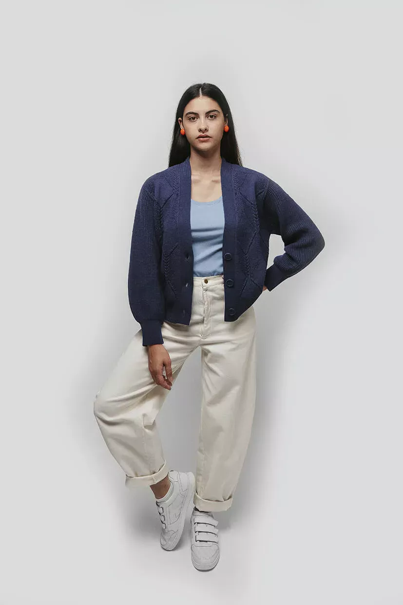 jeune femme brune portant un cardigan bleu et un pantalon blanc